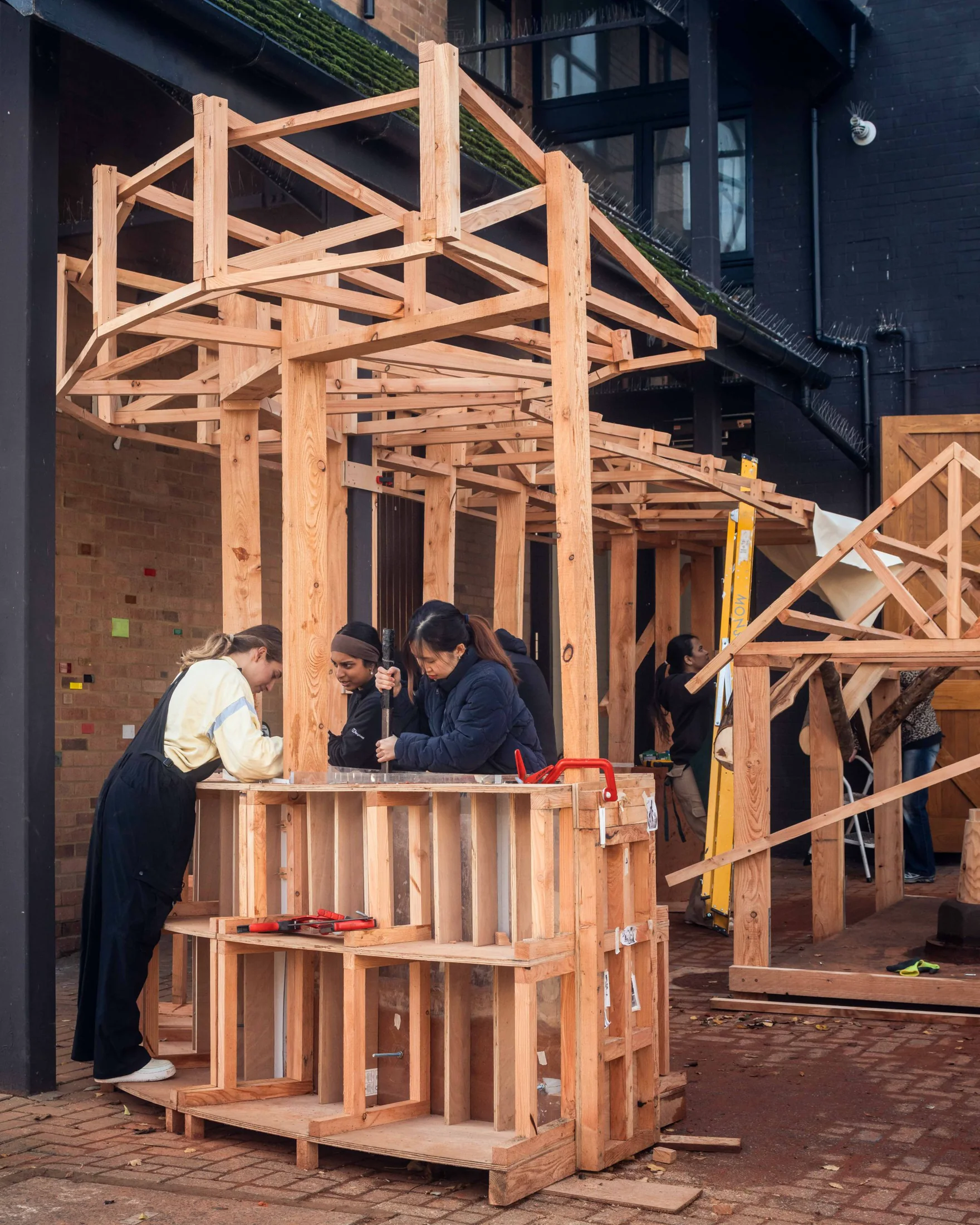 Students assembling the timber framework of the rammed-earth pavilion on the Kingston School of Art campus