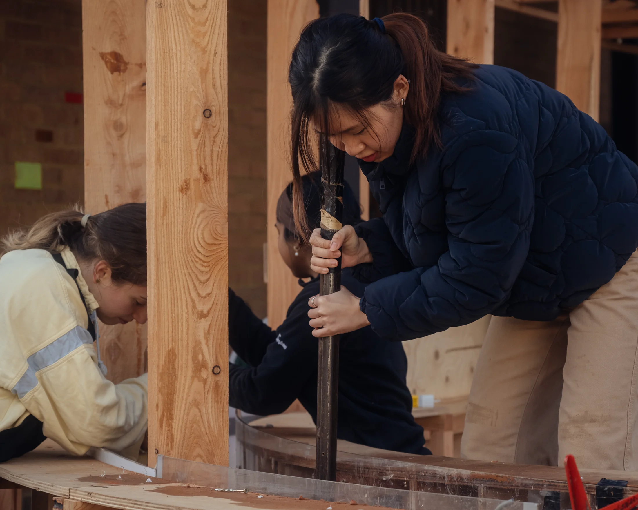 Two students sawing a timber strut on the construction line