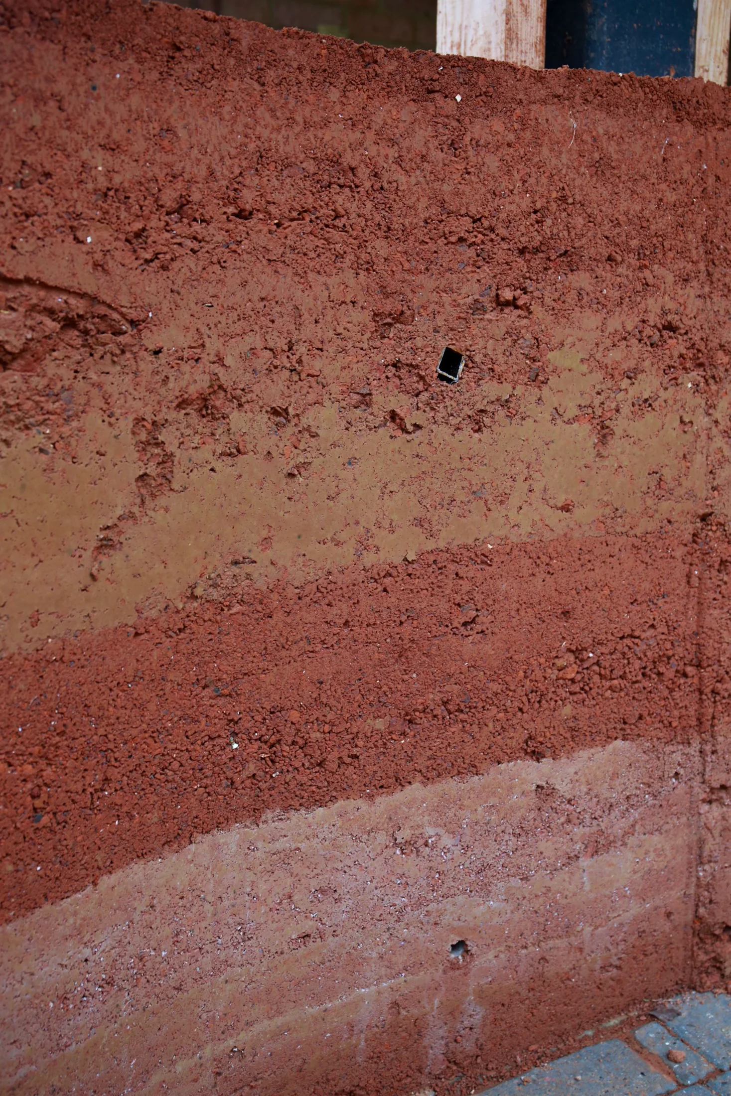 Close-up of the layered rammed-earth wall, showing colour bands from successive pours