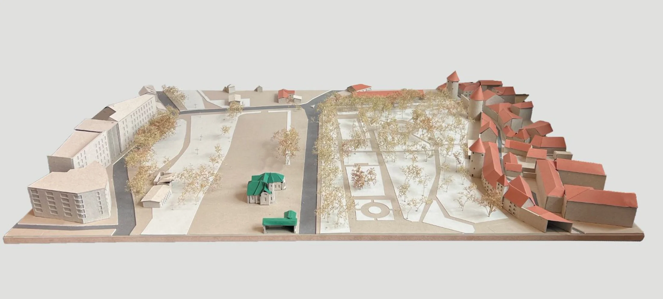 Physical site model showing the empty site between an orange-red historic district to the right and a residential block to the left